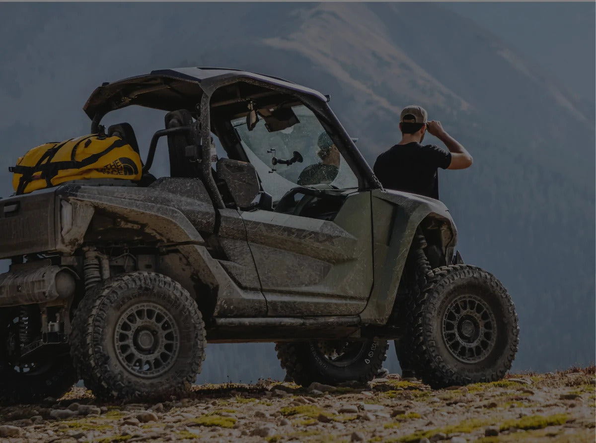 A man looking into the distance standing next to an off-road vehicle
